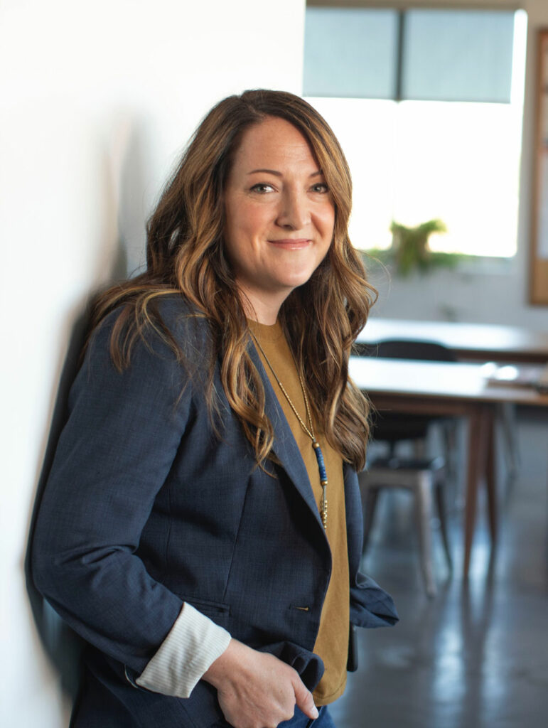 Smiling woman leaning against a wall.